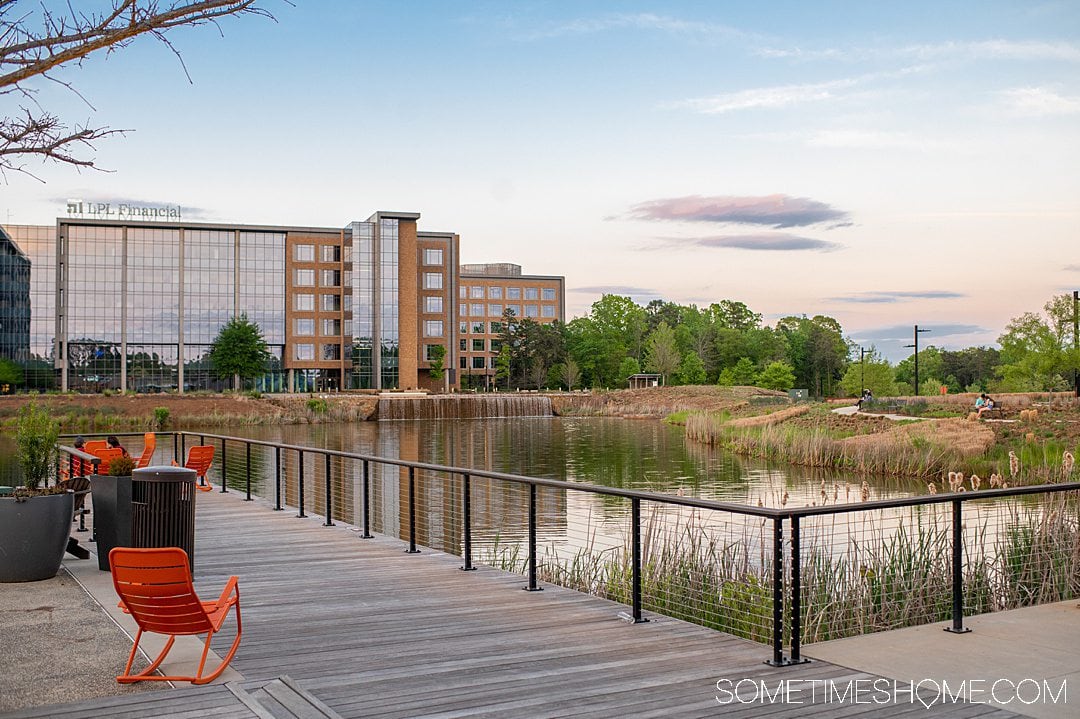 View of a pond and setting sun and a building in the distance, at Kingsley town center in Fort Mill, SC. Going to Kingsley town center is one of the best things to do in York County, SC. 