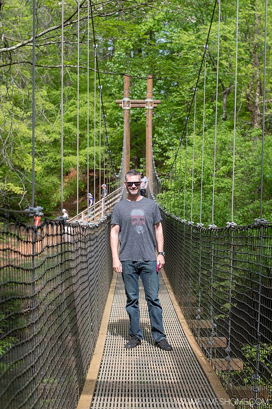Man on the suspension bridge in Fort Miill, SC at Anne Springs Close Greenway.