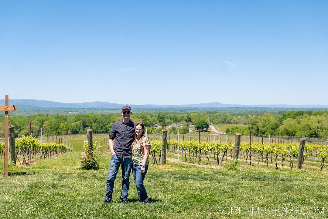 A man and woman in front of a vineyard, at one of the Yadkin Valley wineries in North Carolina.