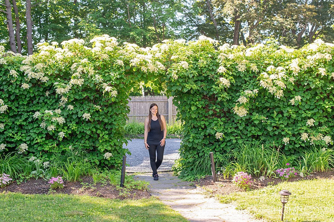 Woman standing inside a natural doorway in a garden with a living wall at a modern bed and breakfast in Bar Harbor, Maine.