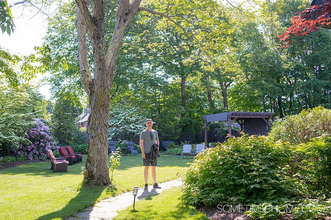 Man standing on a walkway in the garden of a modern bed and breakfast in Bar Harbor, Maine.