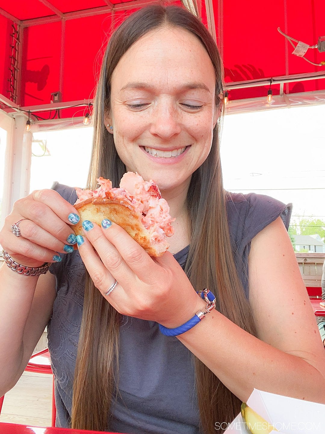 A woman holding and looking at a lobster roll.