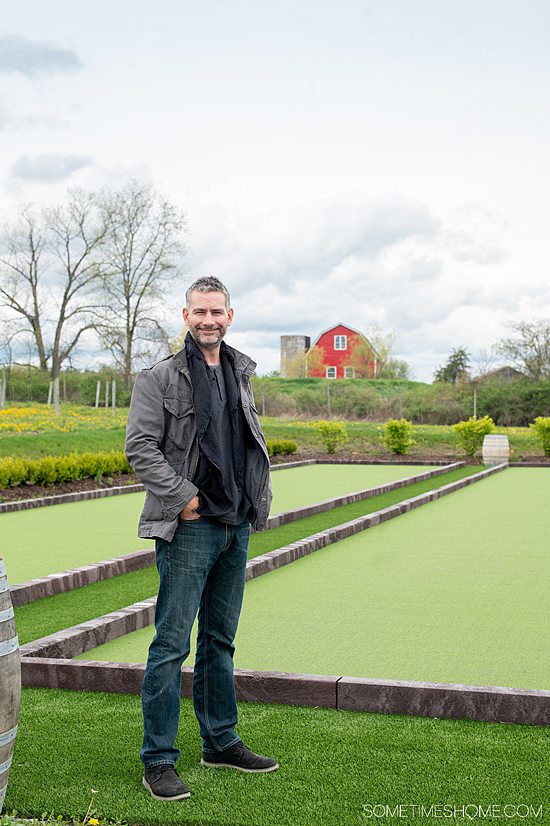 Man in front of a green bocce ball court at Point of the Bluff Vineyards in the Finger Lakes of New York.