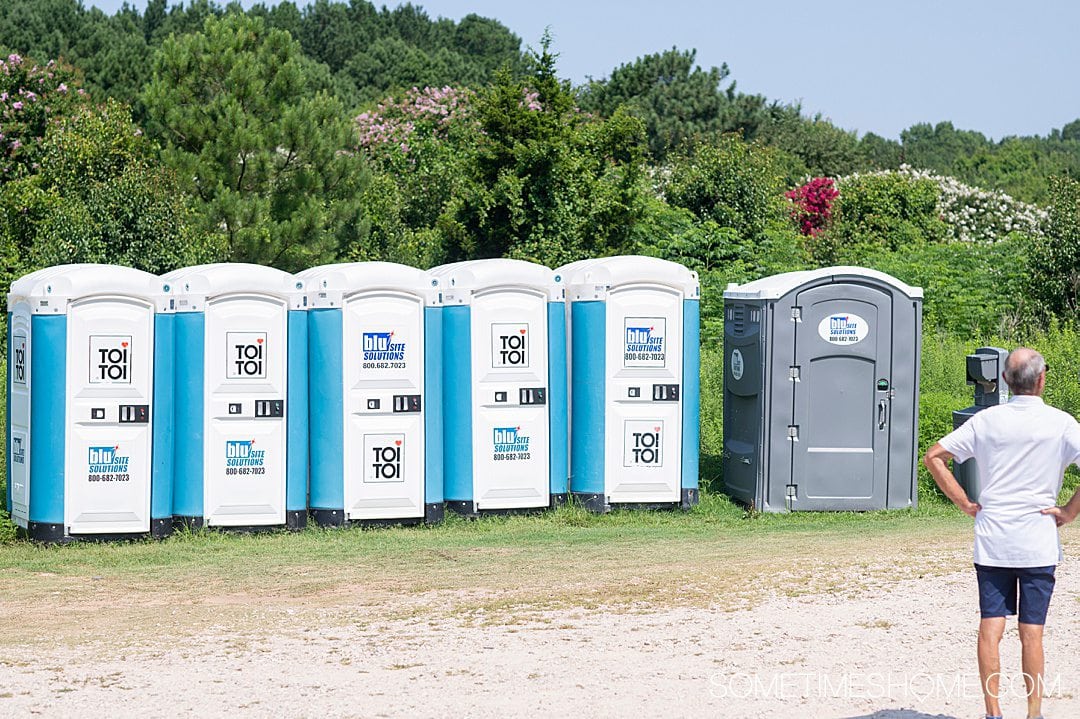 Portable toilets by the sunflower field in North Carolina, with trees behind it. 