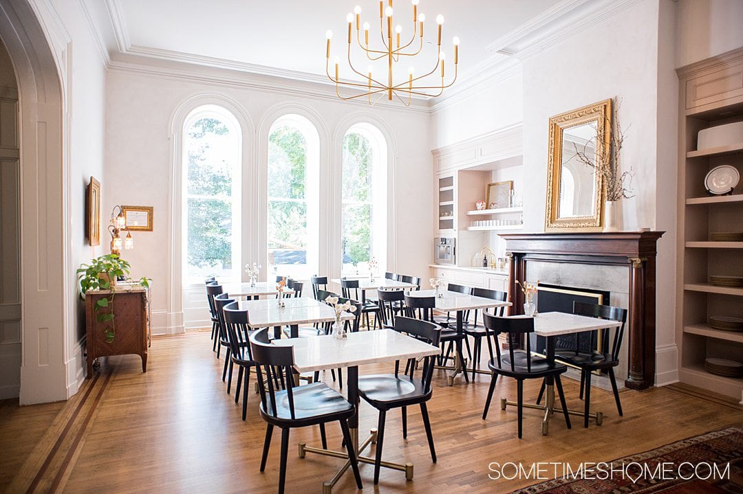 Remodeled dining room with white tables and black chairs at the historic Heights House hotel in Raleigh, NC.
