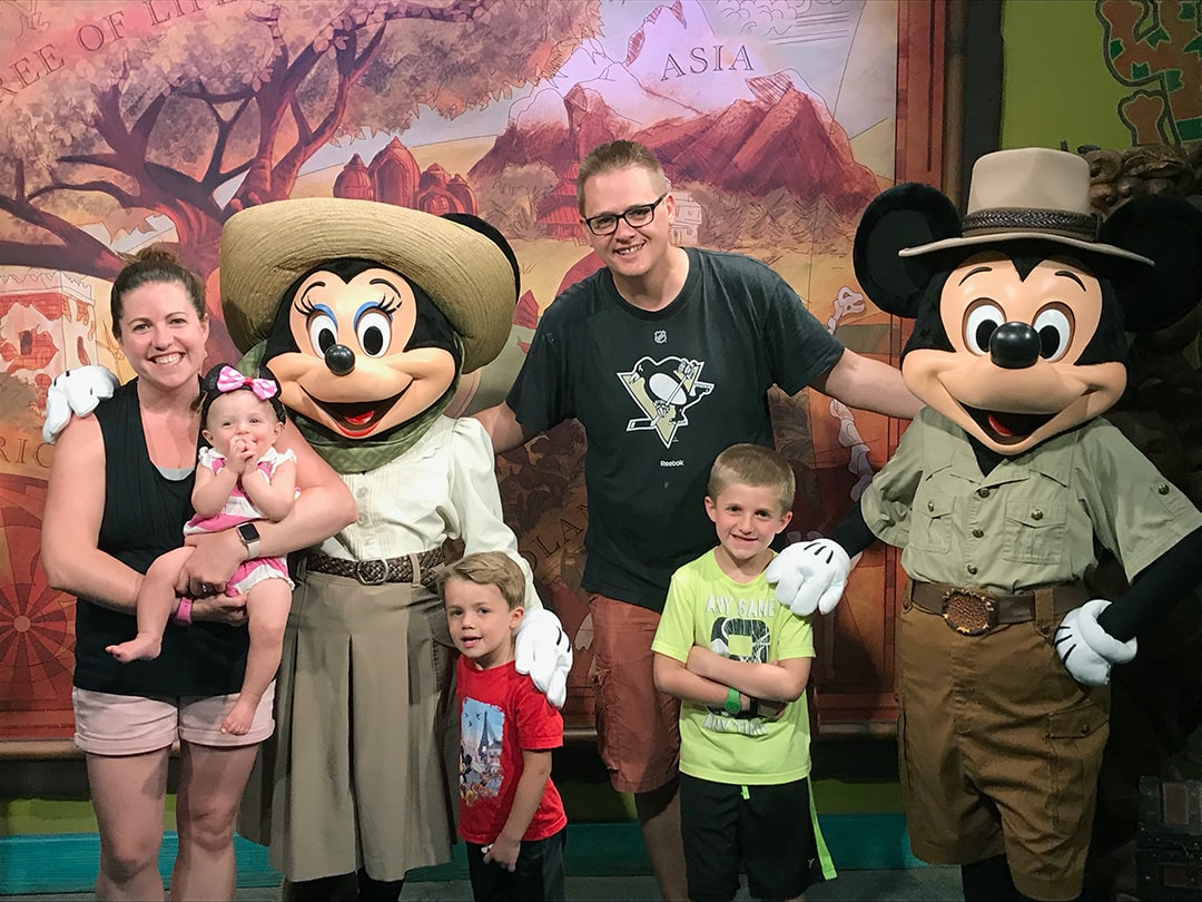 Family photo with Mickey and Minnie Mouse and a forest backdrop behind them.