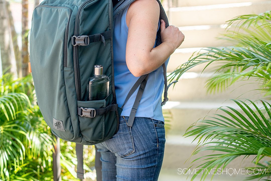 Green CabinZero carry-on backpack with a flat Memo Bottle refillable water bottle.