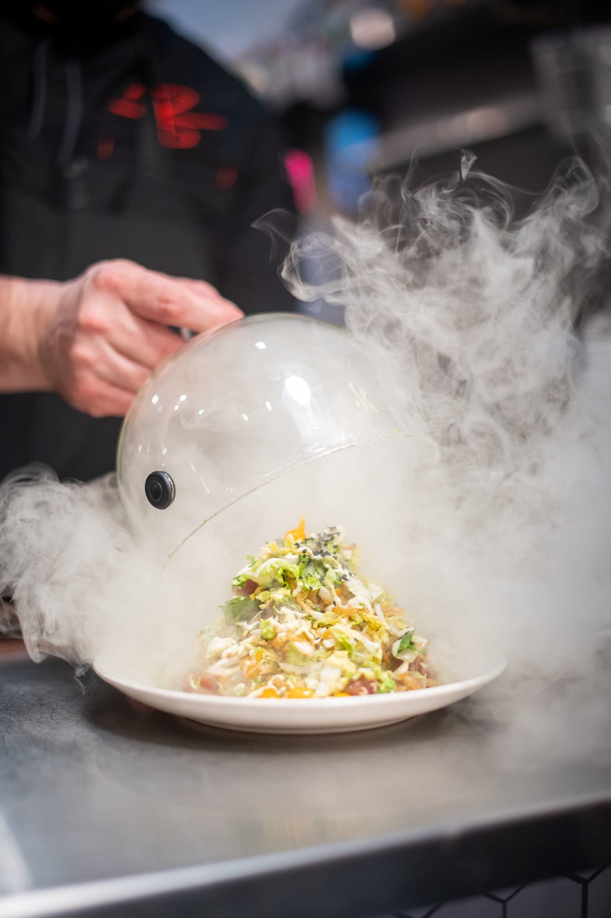 Cloche lifting off a napa cabbage salad with infused smoke.