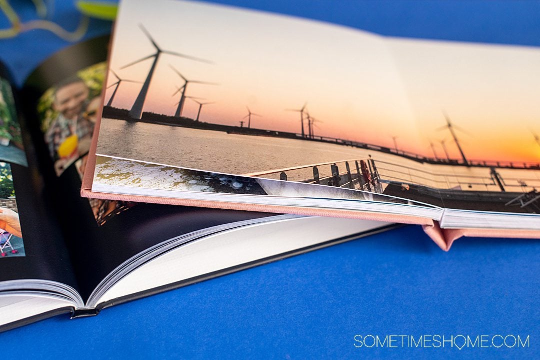 Two photo books open to picture pages on a blue background for an Artifact Uprising review.