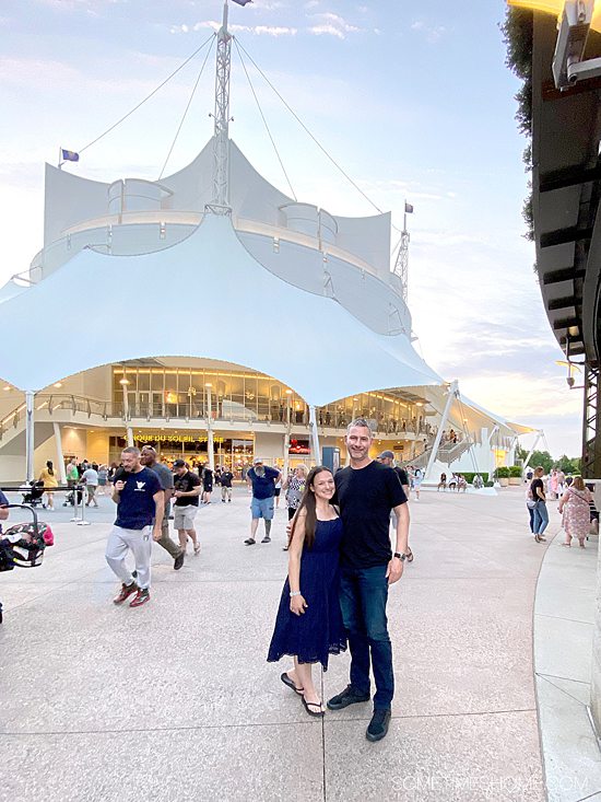 Couple in front of the white Cirque du Soleil theater at Disney Springs West End, at Walt Disney World.