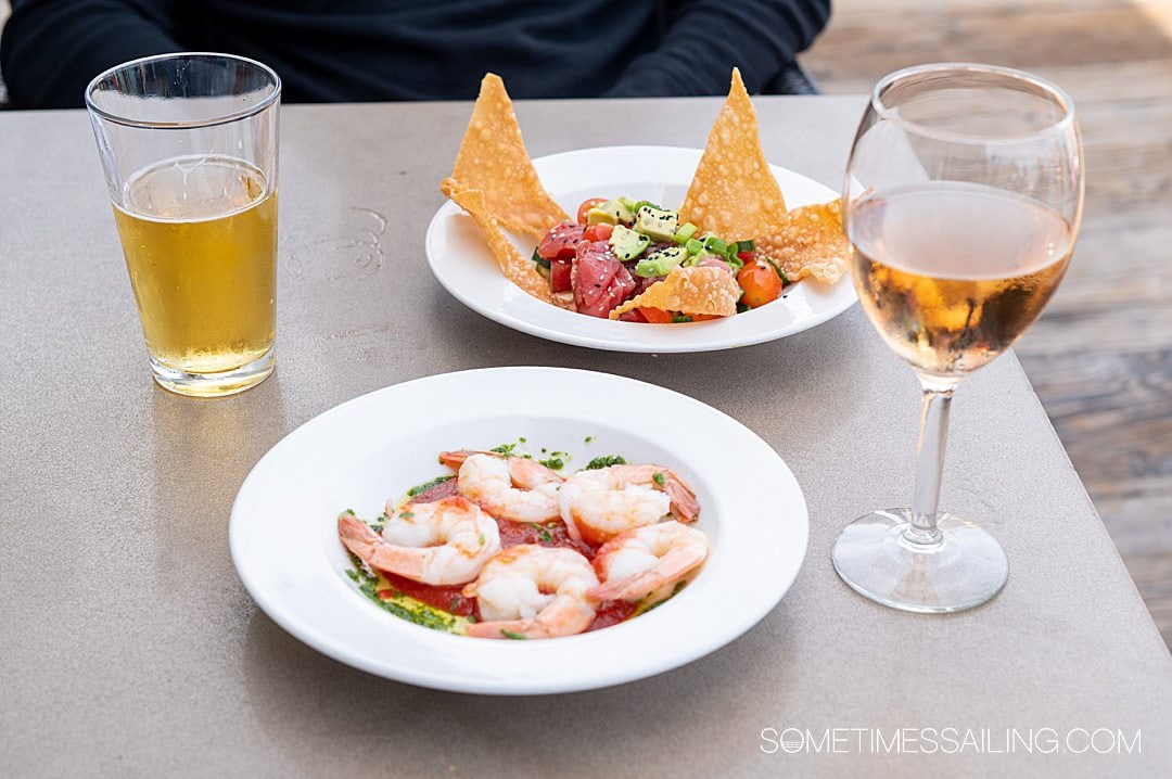 Table with a beer on the left and wine glass on the right, with a bowl of shrimp and ceviche behind it on Catalina Island.