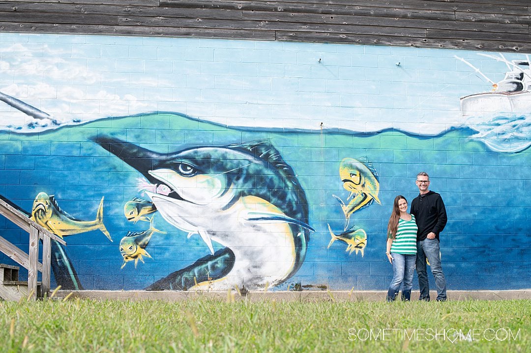 Deep sea fishing near me with a picture of a couple next to a mural of a Blue Marlin fish.