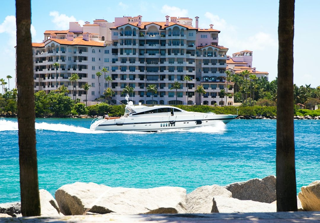 Photo by Enrique Ortega Miranda of a yacht sailing past a high-rise apartment building in Miami's blue waters.