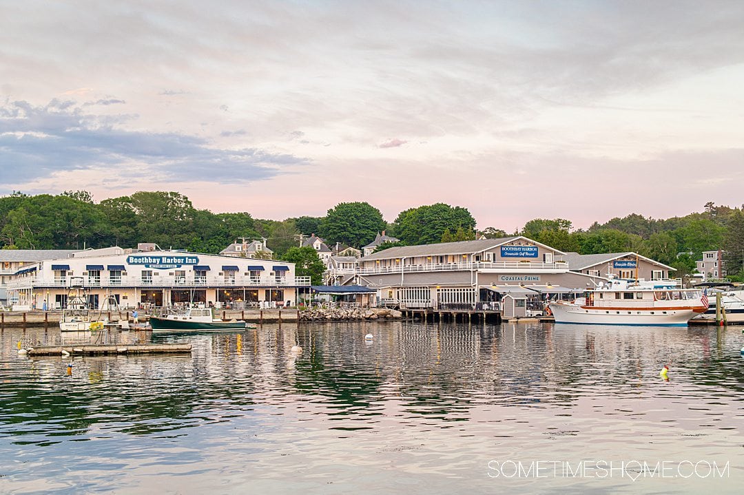 Maine coast sunset with purple and pink clouds, in Boothbay Harbor, part of a Maine coast road trip.