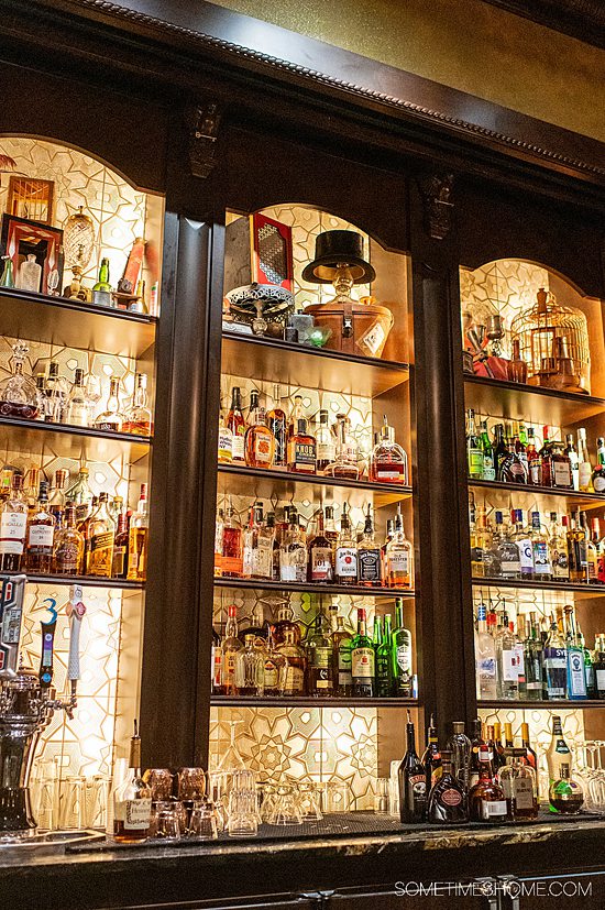 Wall of alcohol bottles with lighting in an otherwise dimly lit bar. Going to AbracadaBar is an adult thing to do on Disney's BoardWalk in Florida.