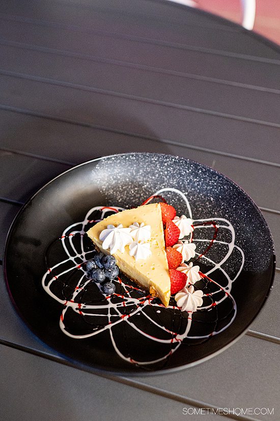 Slice of Key Lime pie on a black plate with white chocolate and raspberry sauce on the place in an atomic pattern at The Space Bar in Titusville, Florida. 