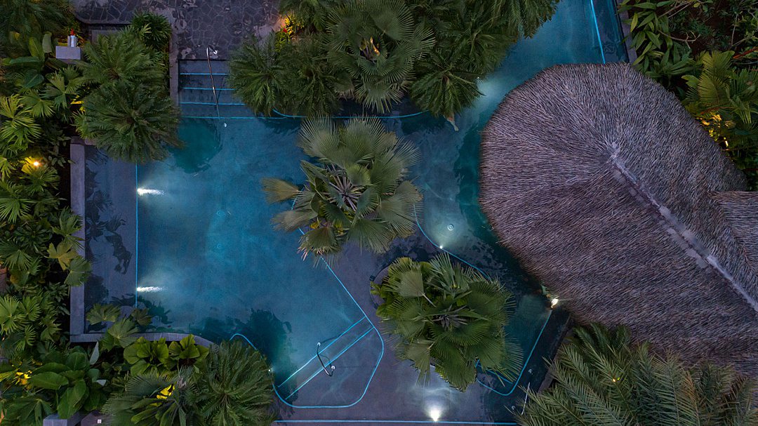 Main pool from an aerial view at Tabacon Resort & Spa, surrounded by lush green trees and plants.