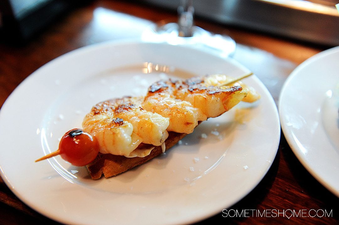 Skewer with shrimp on it topped with a cherry tomato at a tapas restaurant in Spain, for things to eat in Barcelona.