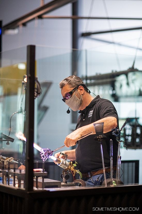 Artist creating glass sculptures at the Corning Museum of Glass, with a blow torch in his hand.