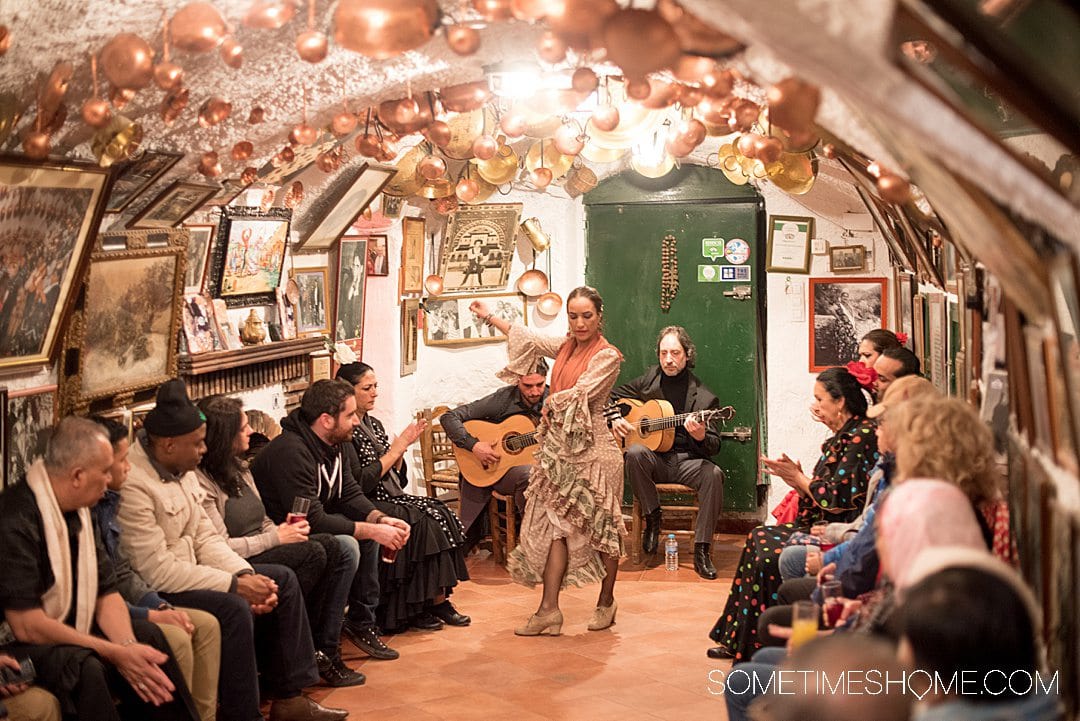 Woman dancing flamenco in one of the best cities in Spain: Granada, in a venue with a low ceiling and copper pots handing from above.