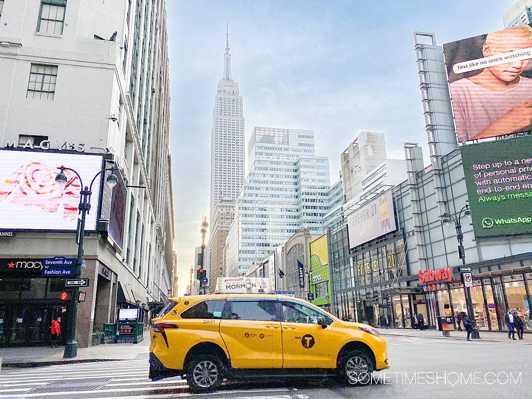 Yellow cab in NYC with the Empire State Building in the distance.