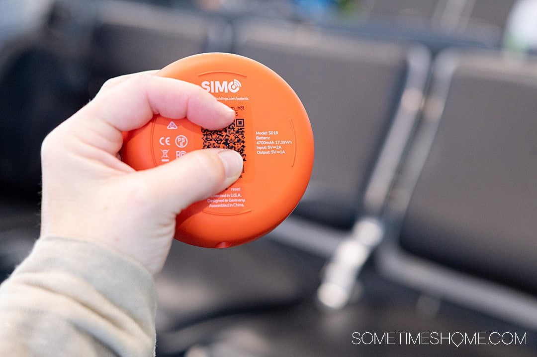 Hand holding a Solis Lite skyroam hotspot device with information on the bottom of the hotspot.