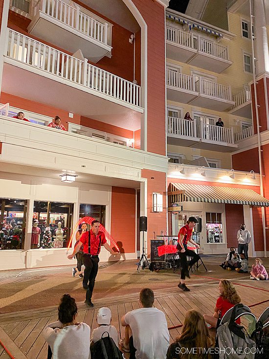 Performers jump roping on Disney's BoardWalk at night with an audience in front of them.
