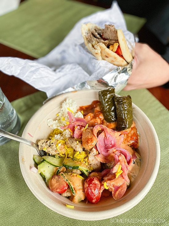 Bowl of Mediterranean rice and vegetables and a hand holding a gyro pita from Yamas Mediterranean.