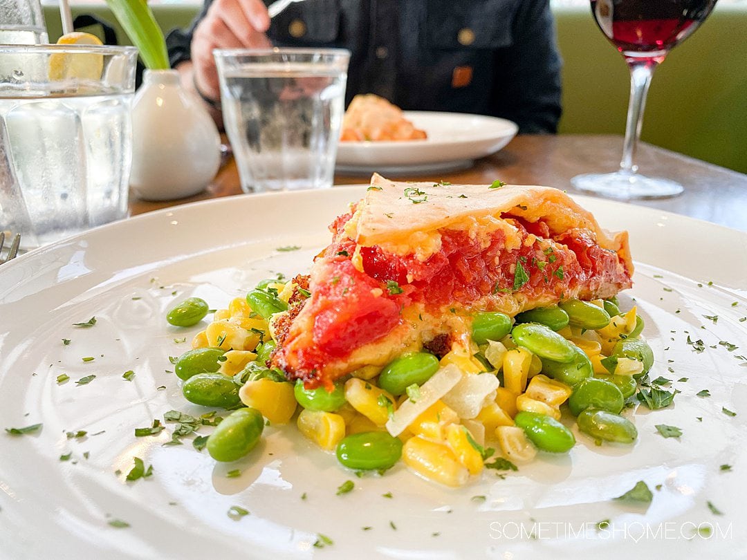 Slice of tomato pie on a bed of corn and edamame succotash from Mozelle's in Winston-Salem.