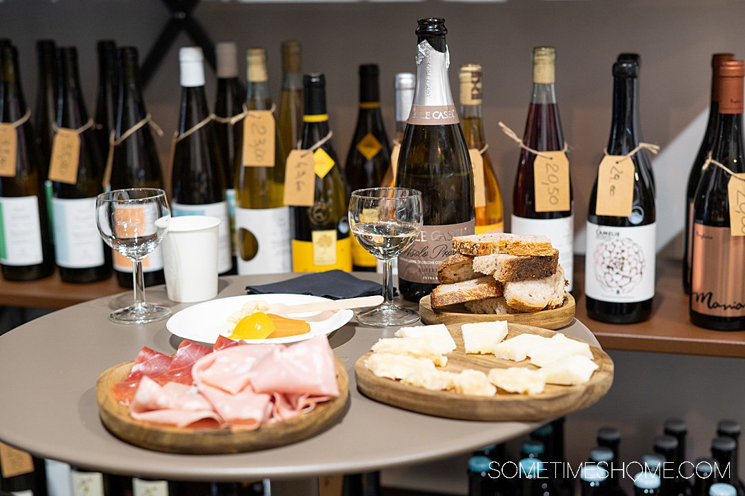 Plates of meat and cheese in front of bottles of wine and an open bottle of Prosecco during a Rome food tour.