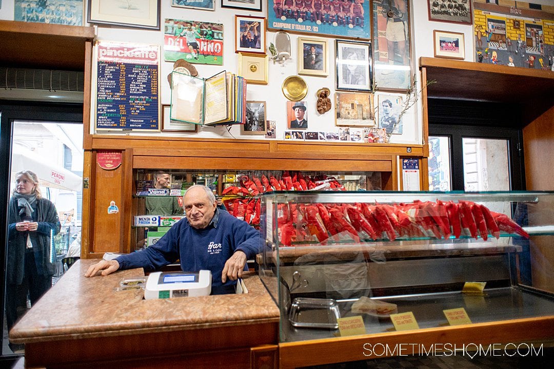 Man at a register in his bar in Rome, Italy, visited during a food tour.