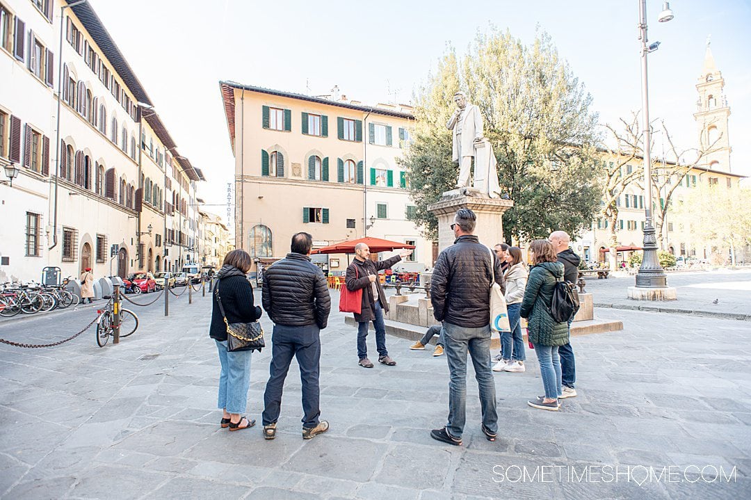 Group of people in front of a statue in Florence, meeting at a Piazza in the city during a food tour.