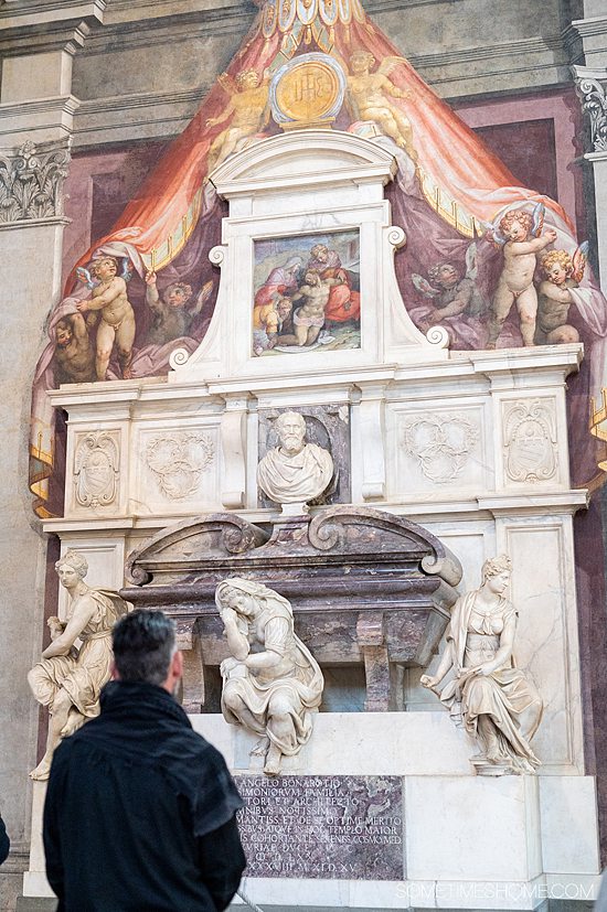 Man looking up at Michelangelo's ornate tomb in Sante Croce church, Florence.