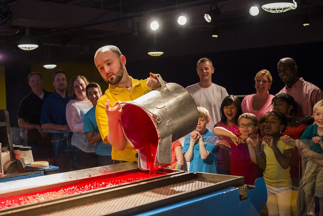 Man pouring a bucket of red liquid wax into a mold at the Crayola attraction in Orlando. 