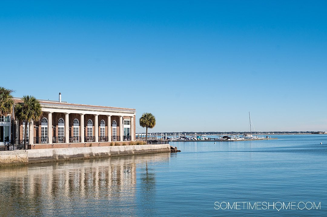Waterfront area of downtown Charleston of a building and blue sky reflecting in the water.