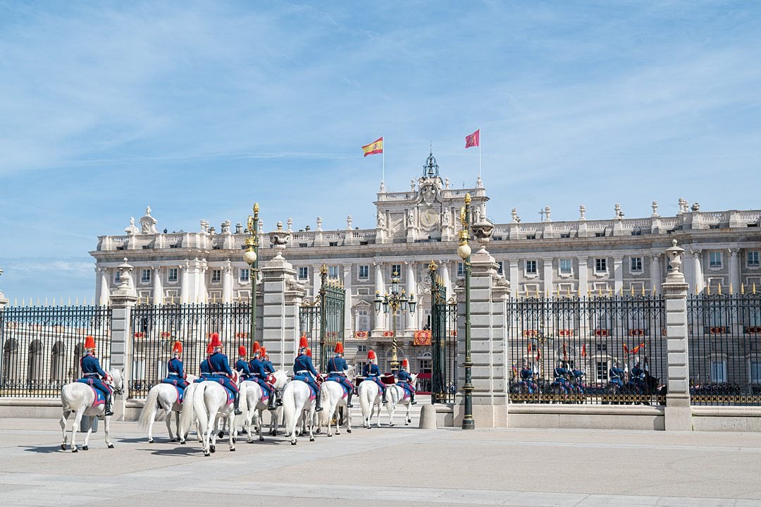 Royal Palace of Madrid facade during an official ceremony in Spain with the Royal Guard on white horses parading in the gates. 
