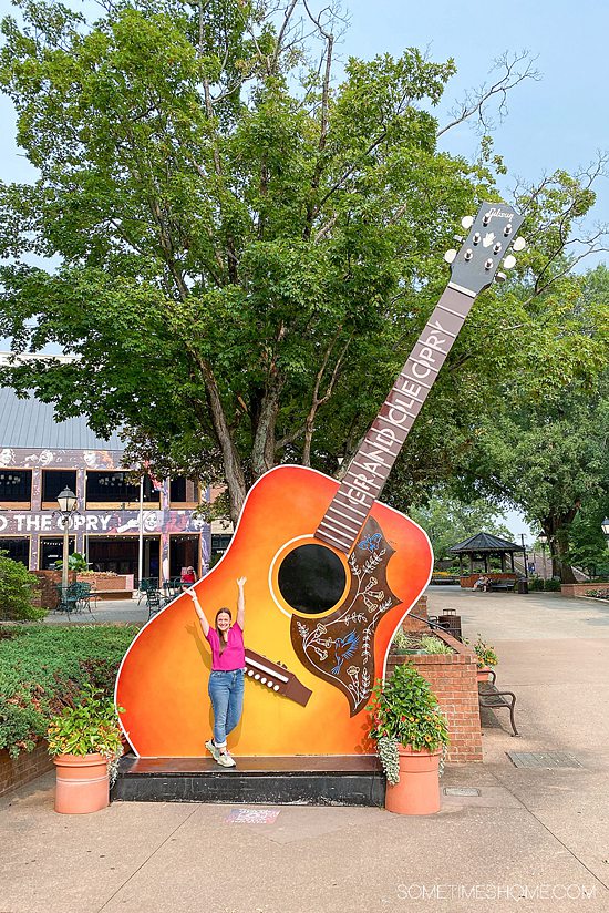 Woman in front of an oversized acoustic guitar sculpture at the Grand Ole Opry.