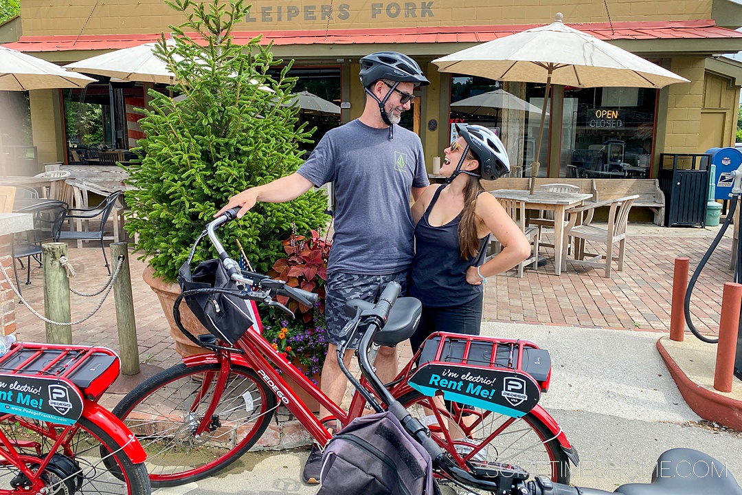 Couple in bicycle helmets looking at each other with a red electric bike in front of them for date ideas in Franklin, TN.