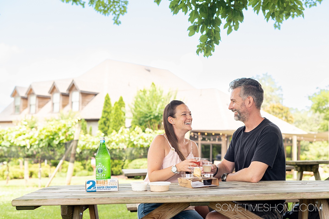 Couple at a picnic table cheersing with wine at Arrington Vineyard.