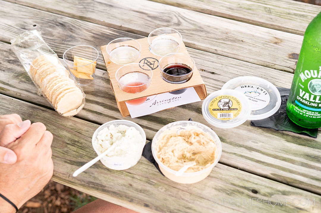 Picnic table with a wine tasting, container of local goat cheese, and smoked fish dip from Franklin, TN.