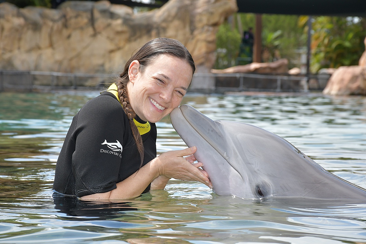 Woman with a dolphin kissing her cheek in the lagoon of Discovery Cove.