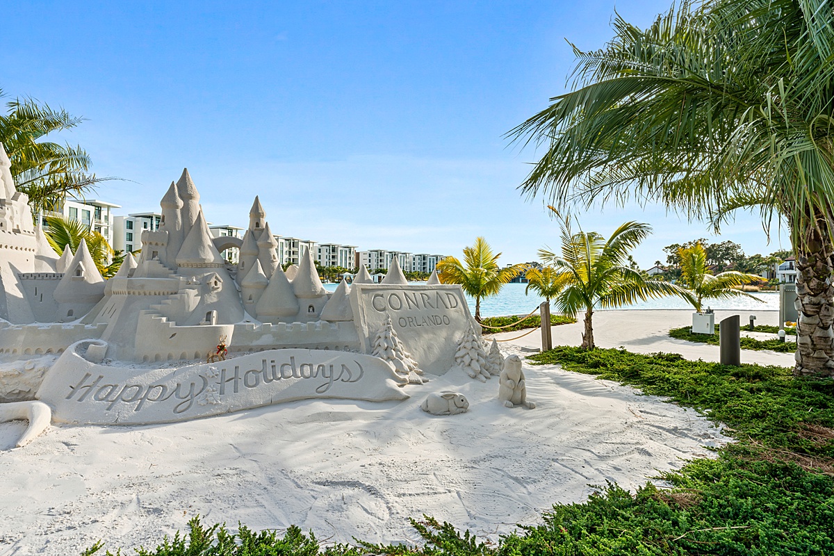 Holiday sand castle at the Conrad, Orlando at Evermore with palm trees surrounding it.
