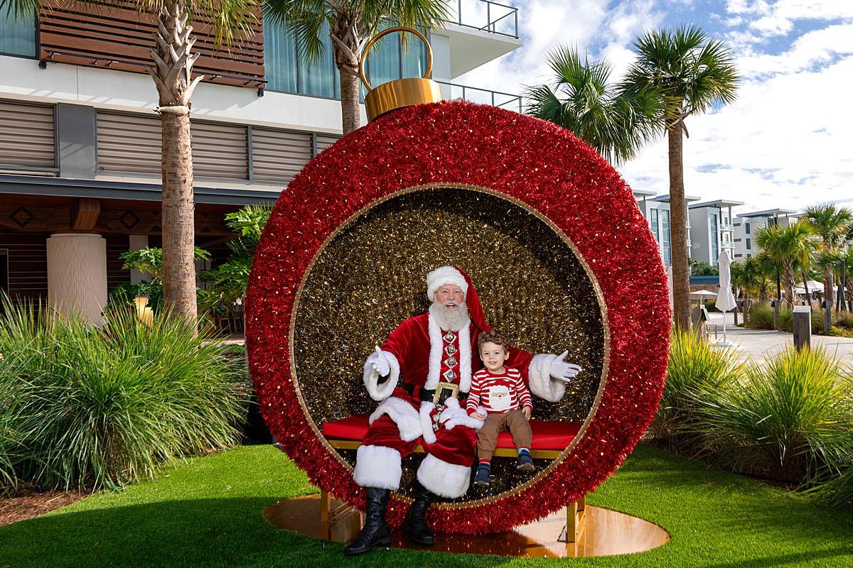 A huge red holiday ornament with Santa Claus and a child sitting next to him at the Conrad, Orlando resort.