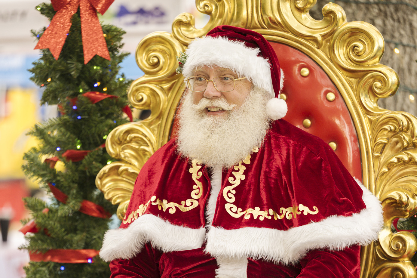 Santa Claus in a red velvet cape with white furry trim.