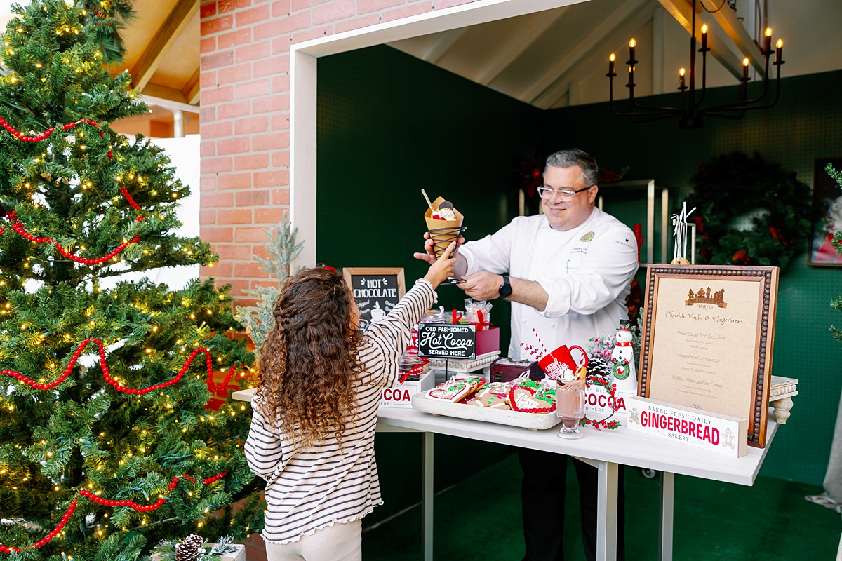 Man hands a little girl hot chocolate at the holiday market in Orlando at the JW Marriott and Ritz Carlton.