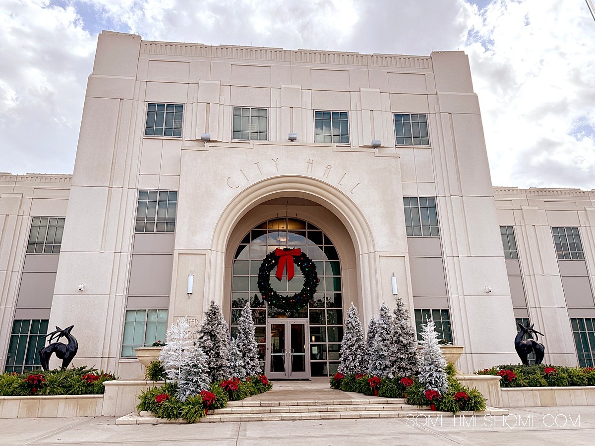 City Hall building in Winter Garden, FL with a wreath in front of it and Christmas trees for the holidays.