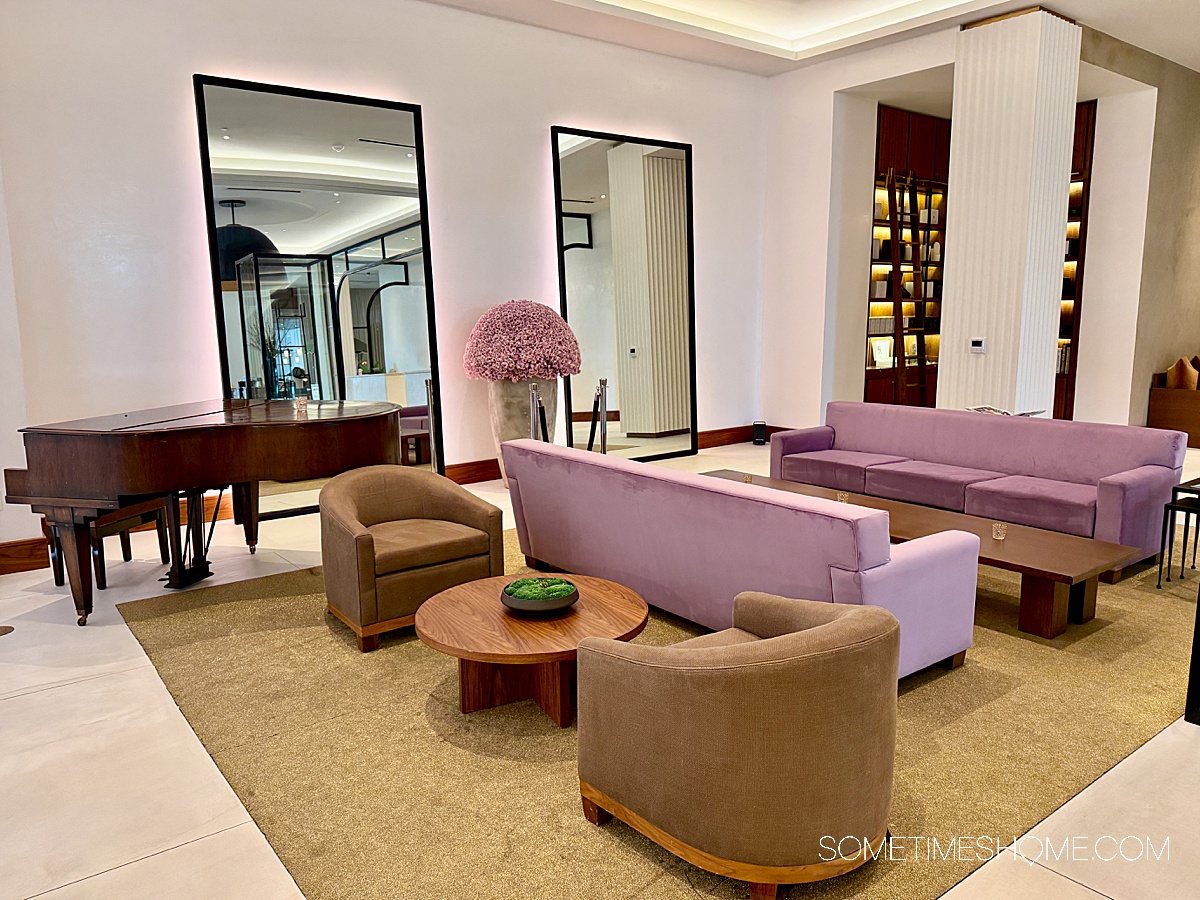 Lobby of the ette hotel, with purple couches and 10 feet tall mirrors with a baby grand piano.