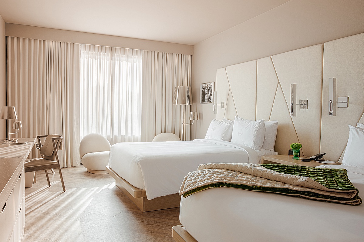 Luxury hotel room with white linens and a green blanket at the ette hotel.