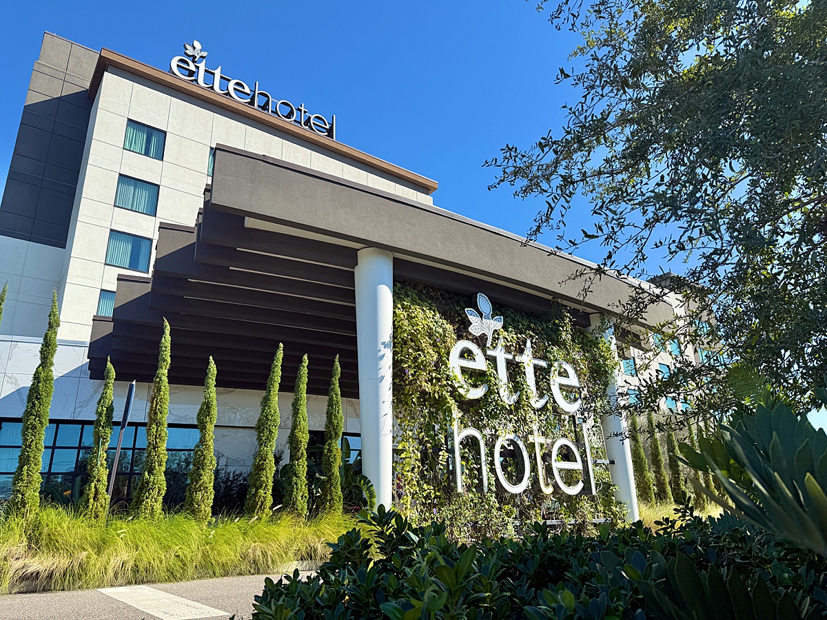 ette hotel entrance covered with greenery on a blue-sky day.