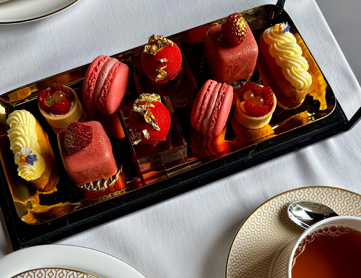 Red and yellow pastries on a silver and black platter during afternoon tea.